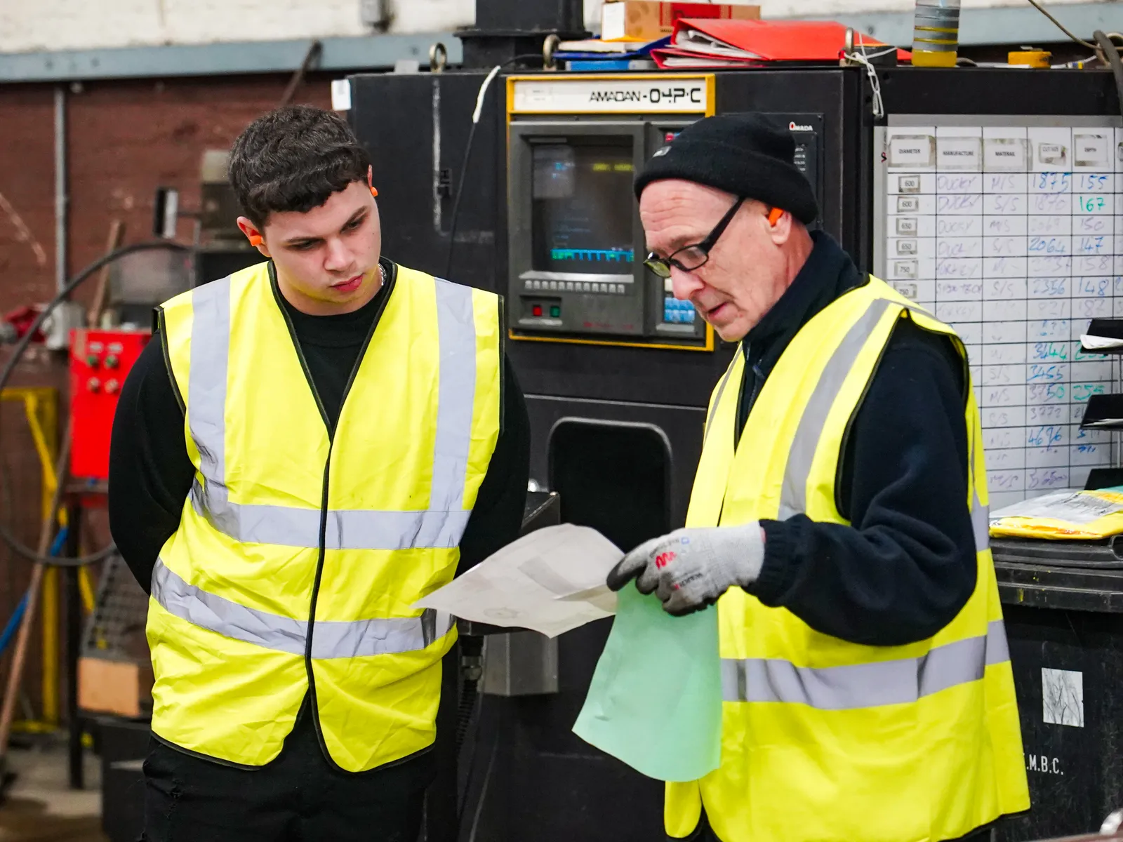 Technicians checking a job against its drawing on the factory floor